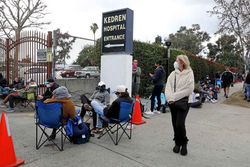 People wait in an unofficial standby line to receive a COVID-19 vaccine at Kedren Community Health Center in South L.A.