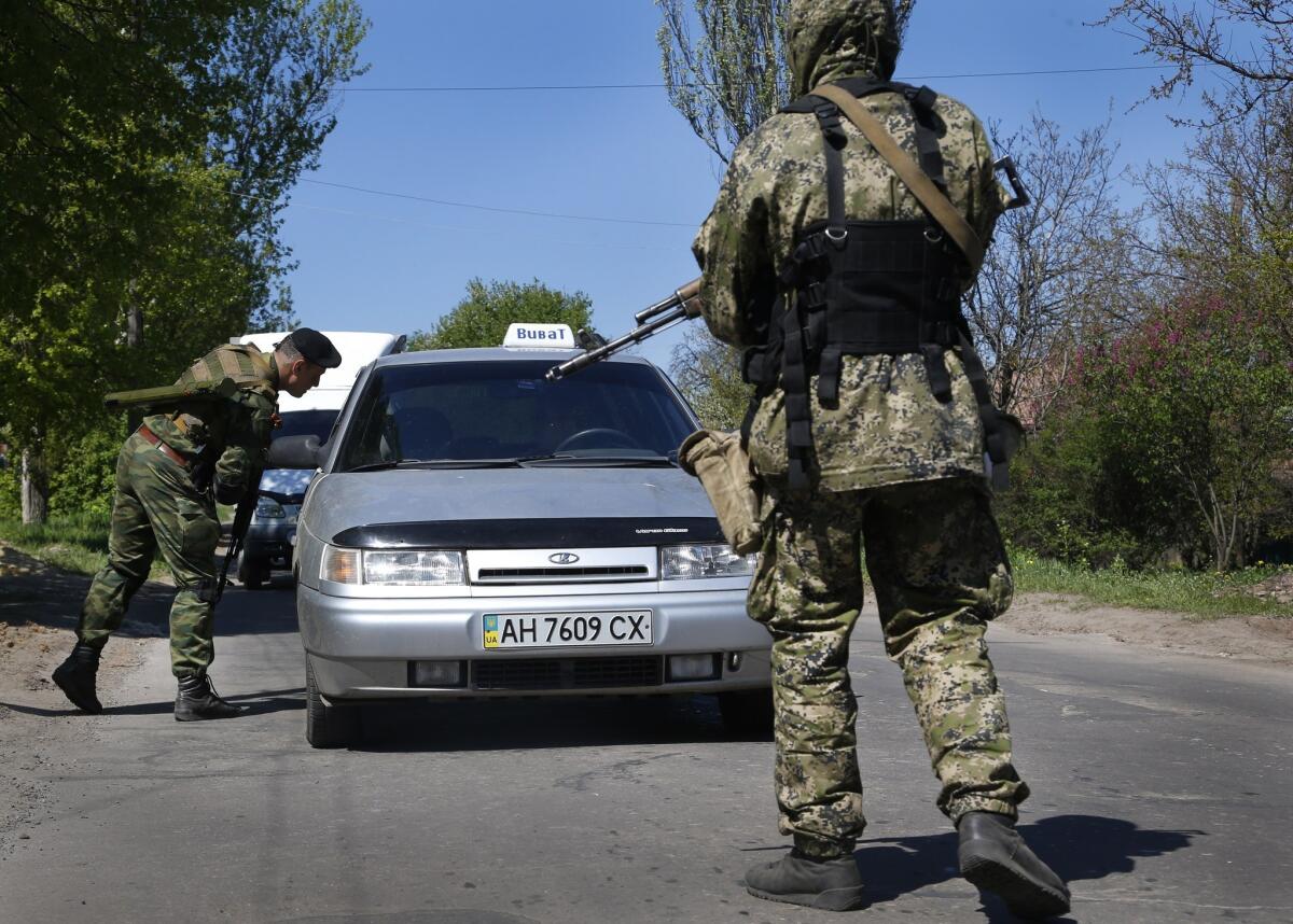Armed pro-Russia militants check vehicles at a roadblock near Slovyansk, in eastern Ukraine. A bus carrying a 13-member military monitoring team from the Organization for Security and Cooperation in Europe was detained by separatist gunmen on Friday as it attempted to enter the city on a mission authorized by the 57-member alliance, which includes Russia and Ukraine.