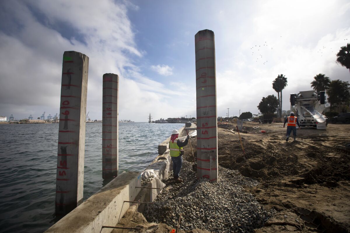 Crews at a construction site with concrete pillars next to the harbor