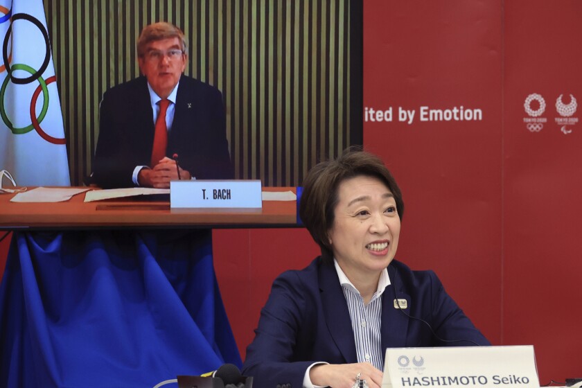 IOC President Thomas Bach on a screen and Seiko Hashimoto sitting nearby