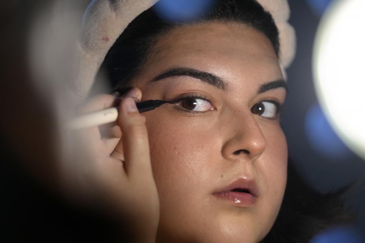 A woman uses a mirror while applying makeup