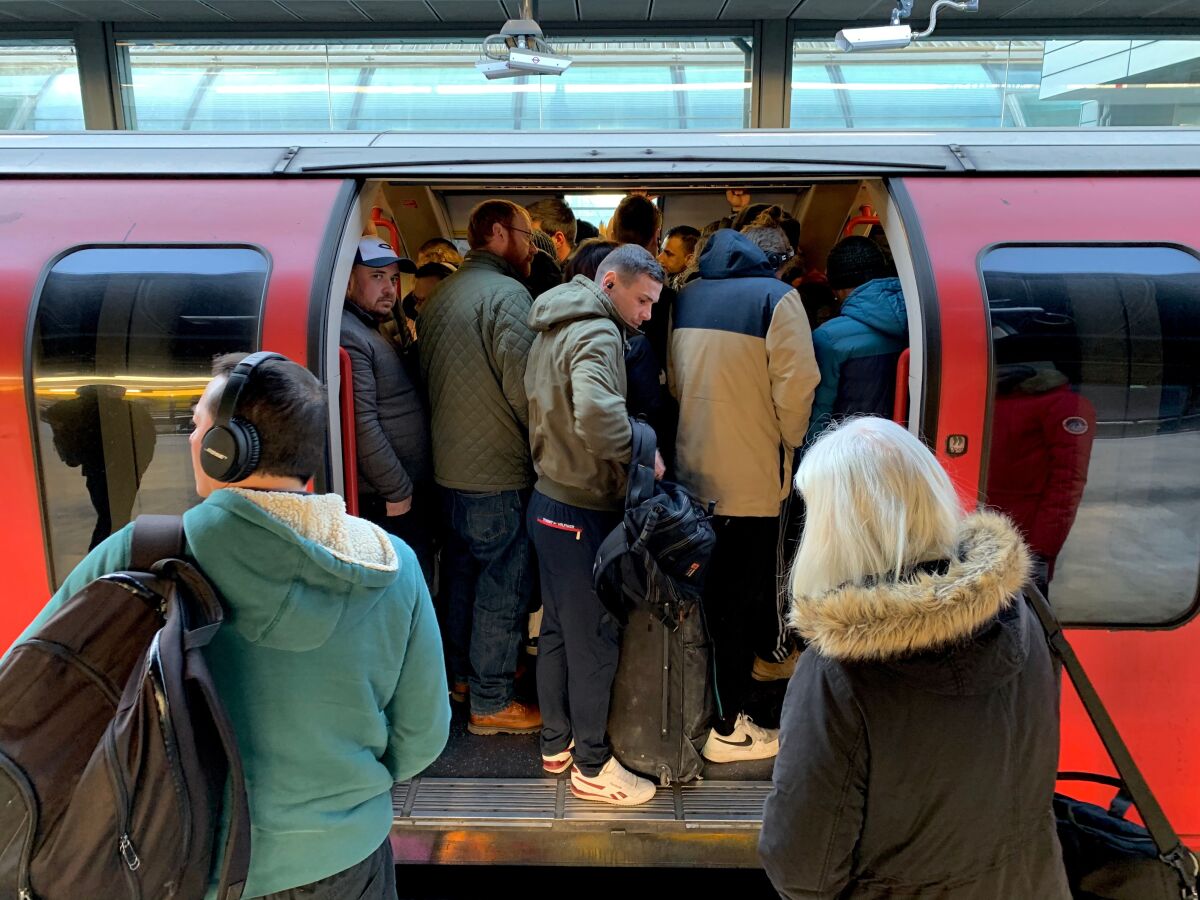 Passengers squeeze onto a busy train at Stratford station in London on March 23, 2020.