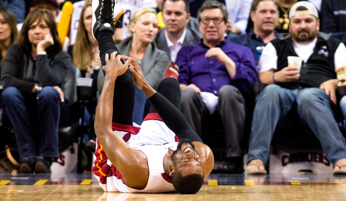 Heat guard Dwyane Wade holds his knee after getting injuring during a game against the Cavaliers on Thursday night in Cleveland.