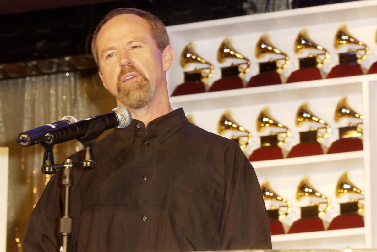 Mike Greene in front of a wall of Grammy award statuettes