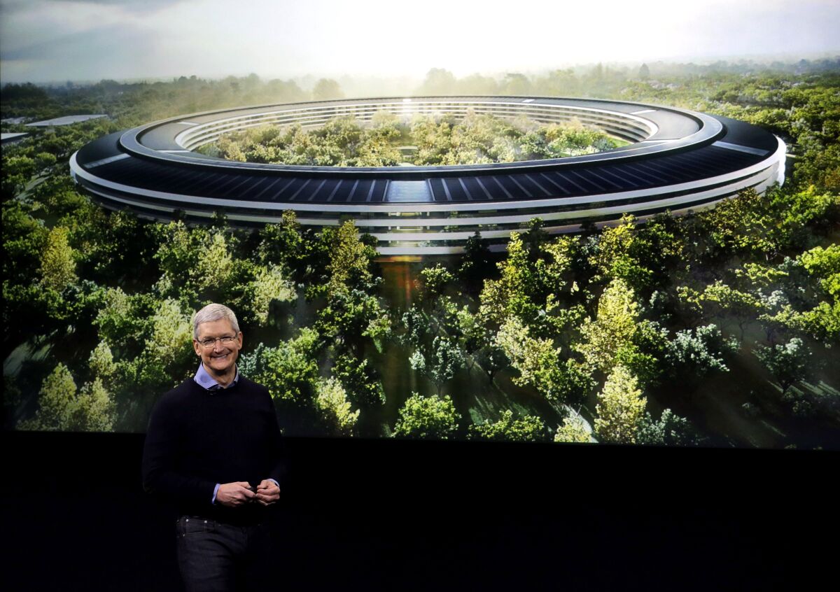 Apple's Tim Cook stands in front of a rendition of a new company building.