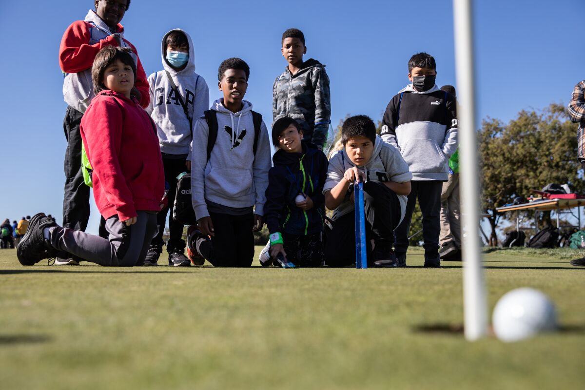 Students from Millennial Tech Middle School watch a ball while measuring green speed with a stimpmeter at Torrey Pines.