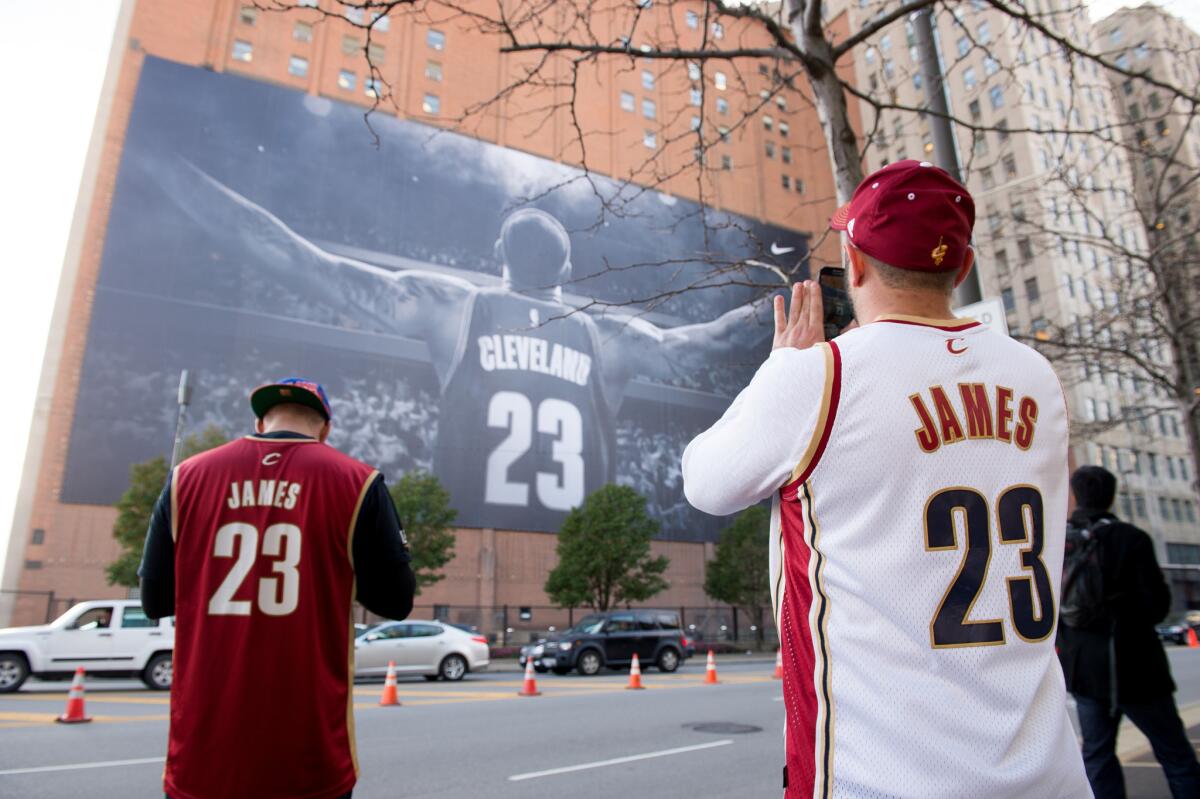 Fans take pictures of a larger-than-life LeBron James banner outside Quicken Loans Arena on Oct. 31 before James' first regular-season game back in Cleveland. James scored only 17 points that night during the Cavaliers' loss to the Knicks.