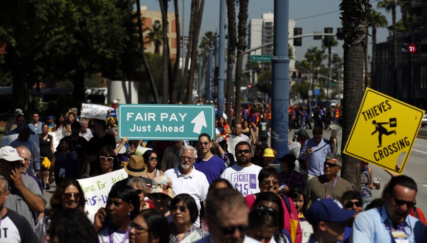 Marchers in Long Beach in September call for increasing the minimum wage. The city last month adopted a timeline that will increase the base wage to $13 by 2019 and potentially to $15 two years later.