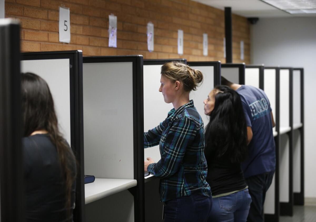 Glenn Woerndle, center, of Orange, registers to vote and takes her driver's test using a touch-screen machine in Santa Ana.