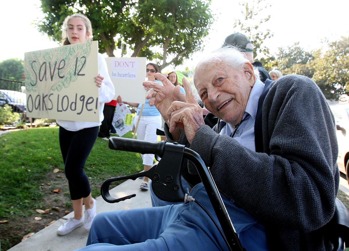 12 Oaks Lodge resident Dean Deardorf, 96, happily moves his hands to the beat of the chant yelled by a long line of protesters marching in front of be.group in Glendale. Locals protested the closing of Twelve Oaks Lodge in La Crescenta, where Deardorf lives, on Wednesday, Oct. 2, 2013. Nearly 125 people protested in front of the Glendale business.