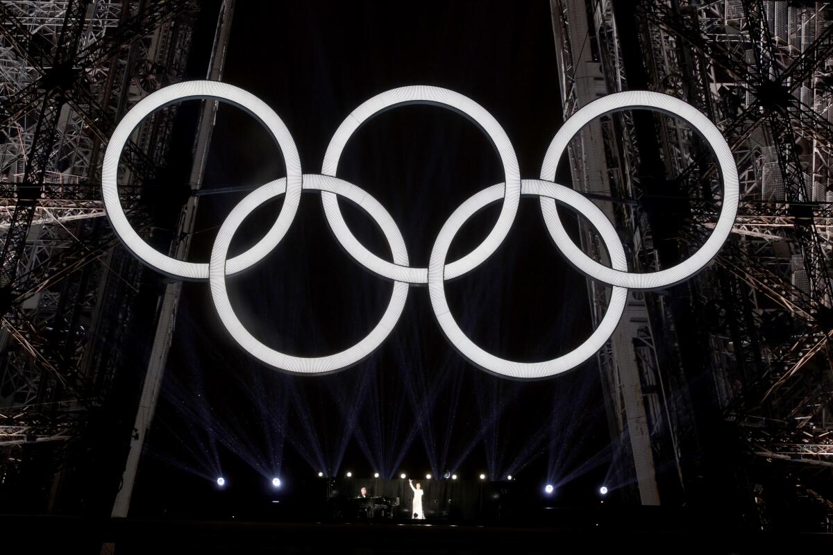 The Olympic rings lit above Celine Dion on the Eiffel Tower.