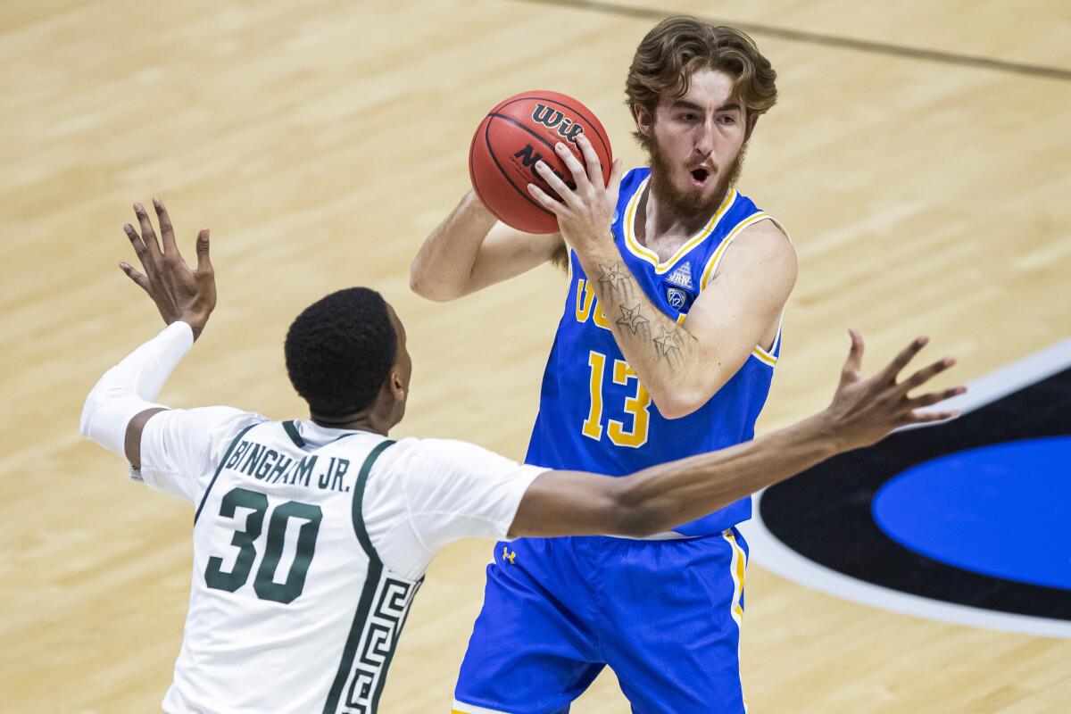 UCLA's Jake Kyman looks to pass around Michigan State's Marcus Bingham Jr. during the Bruins' First Four win on March 18.