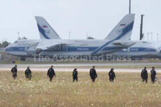 Police officers are walking across a field on the grounds of Leipzig Airport, in Schkeuditz, Germany, Friday, Aug. 7, 2026, searching for a drone that may be connected to a suspected attack. (Sebastian Willnow/dpa via AP)