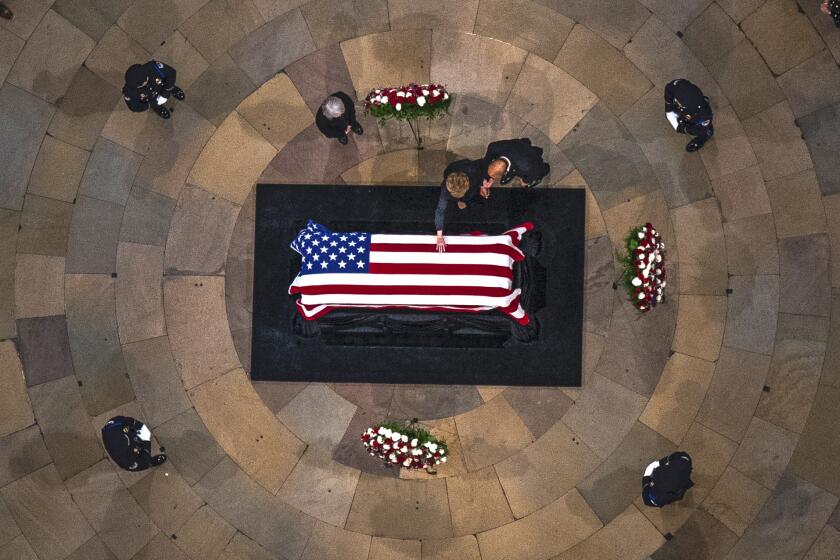 Elizabeth Dole touches the casket of her husband, former Sen. Bob Dole, R-Kan., as he lies in state in the Rotunda of the U.S. Capitol, Thursday, Dec. 9, 2021, on Capitol Hill in Washington. (AP Photo/Andrew Harnik, Pool)