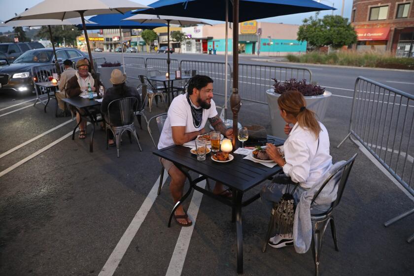 LOS ANGELES, CA - JULY 25: Brandon Astudillo, center and wife Rose Astudillo, of Glendale, dine outdoors at Baracoa Cuban Cafe in Atwater Village on Saturday, July 25, 2020 in Los Angeles, CA. Restaurant on-site dining limited to outdoor seating due to Covid-19 restrictions in Southern California. Most of the tables are being set up on wide sidewalk areas, or in parking spaces adjacent to the restaurants. (Gary Coronado / Los Angeles Times)
