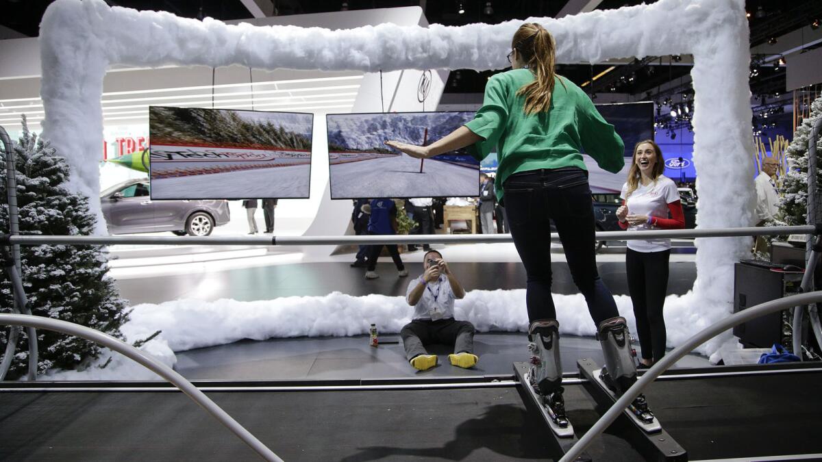 A woman tries out a downhill skiing simulator at the Los Angeles Auto Show on Wednesday.