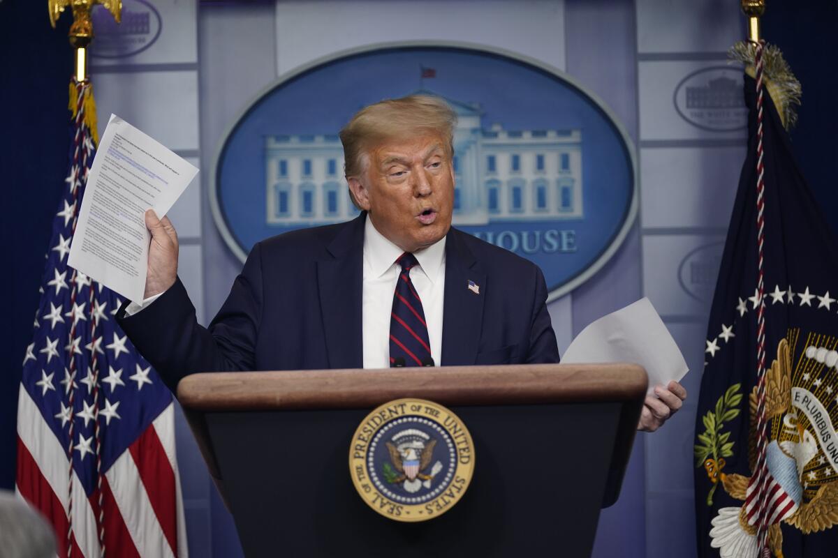 President Trump holds articles as he speaks during a news conference at the White House on Thursday. 