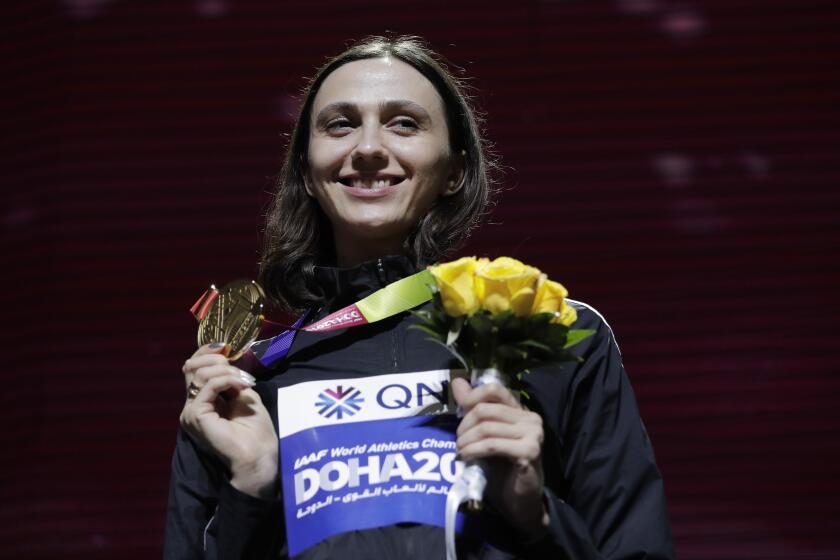 FILE - In this Tuesday, Oct. 1, 2019 file photo, Gold medalist Mariya Lasitskene, who participates as a neutral athlete, poses during the medal ceremony for the women's high jump at the World Athletics Championships in Doha, Qatar. Three-time world high jump champion Mariya Lasitskene has assailed Russian track leaders after they were charged with using fake medical documents during an investigation. Lasitskene has called for swift and radical reforms and the removal of officials appointed by track federation president Dmitry Shlyakhtin. (AP Photo/Nariman El-Mofty, File)