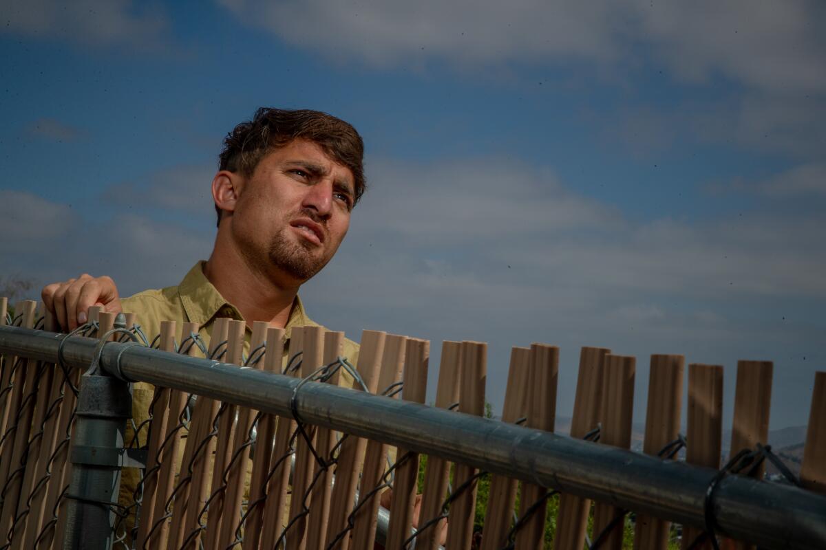 A person stands behind a fence.