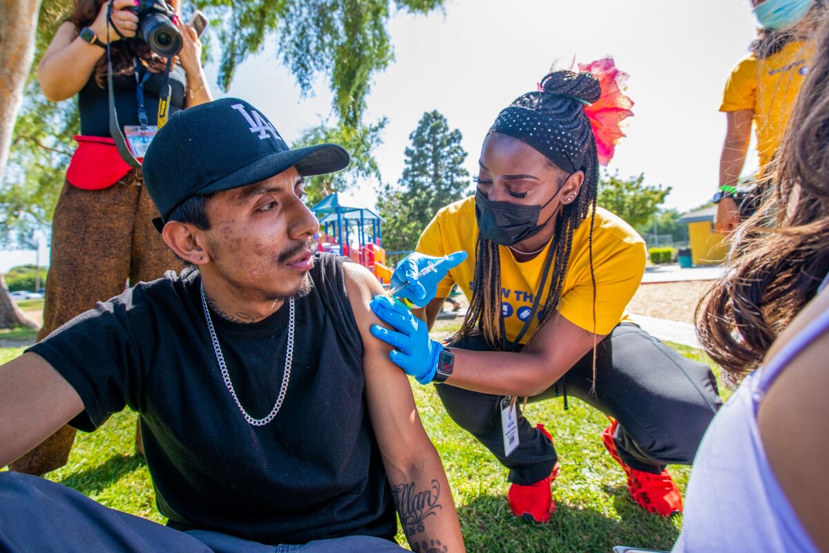 Asia Hartford gives Luis Fernandez a vaccine at a park