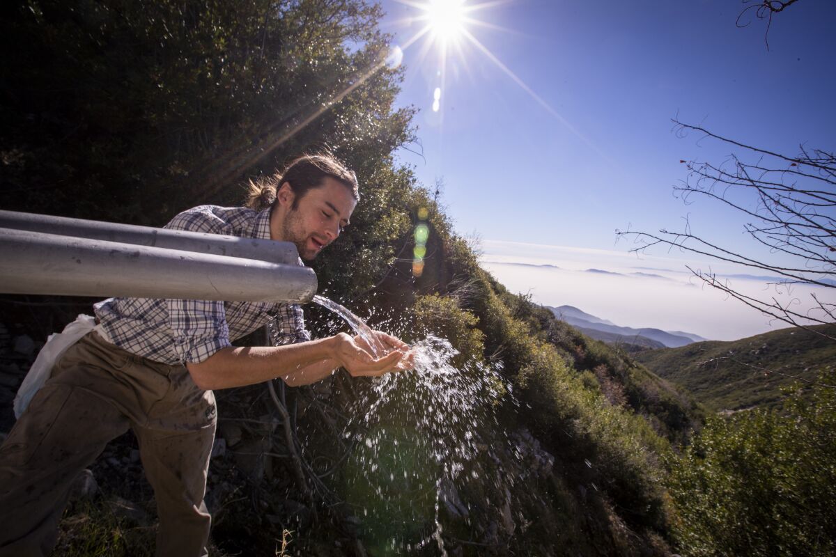 A man washes his hands with spring water pouring from a pipe in the San Bernardino Mountains