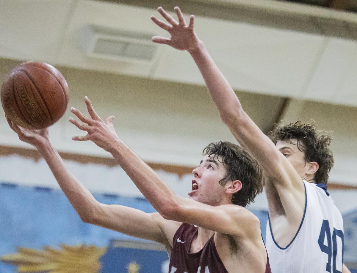 Laguna Beach's Nolan Naess goes up for a shot as Newport Harbor's Luke Bashore attempts to block it from behind in a Sunset Conference crossover game on Friday.