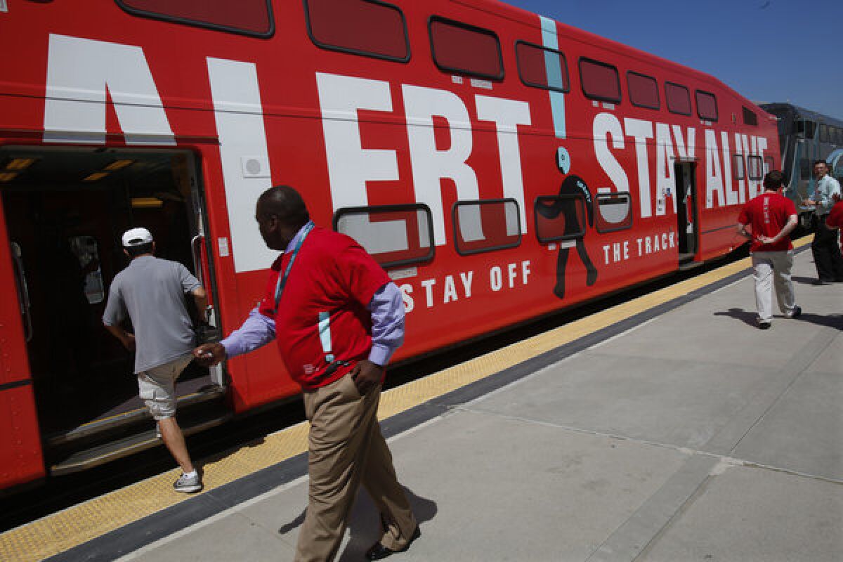 Members of the public check out a Metrolink train at Union Station in Los Angeles that has been wrapped in a warning sign for Rail Safety Month.