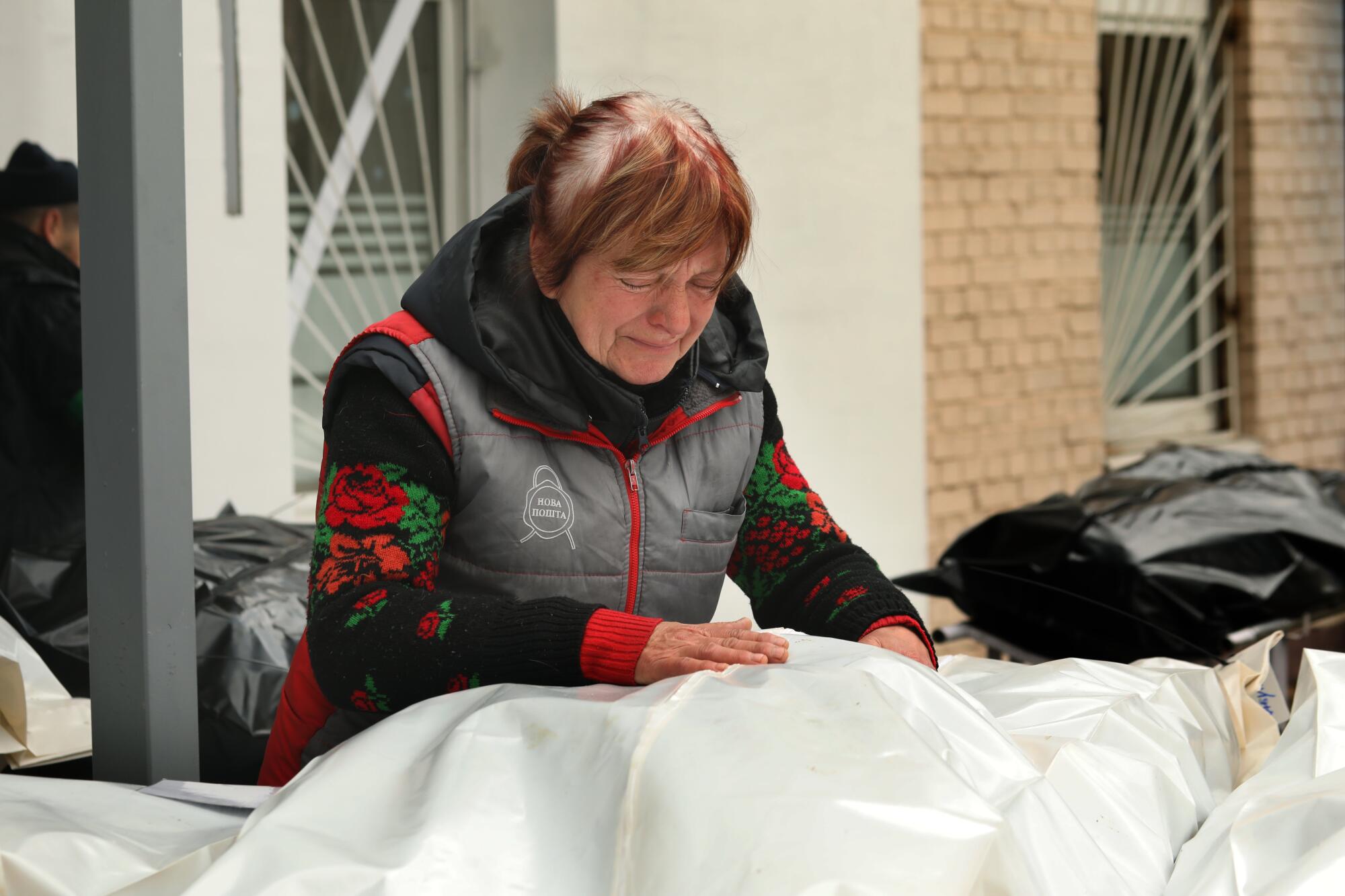 Zena Laboonska leans over the body of her son whose hair was visible through the plastic body bag, the number 126 tied to it