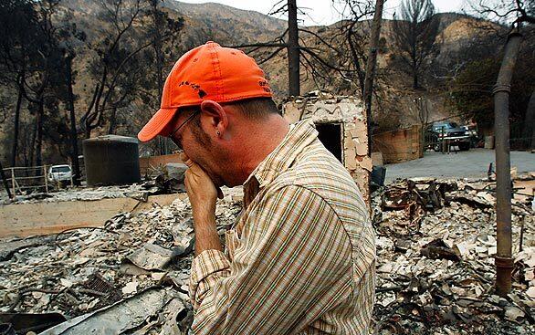 A man who identified himself only as Adi is overcome with emotion as he surveys the charred ruins of his home Wednesday in the 2400 block of Stonyvale Road in Tujunga.