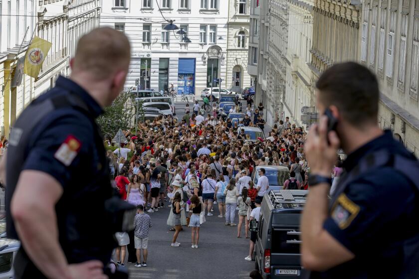 Policías austríacos observan a admiradores de Taylor Swift reunidos en el centro de la ciudad en Viena, el jueves 8 de agosto de 2024. (AP Foto/Heinz-Peter Bader)