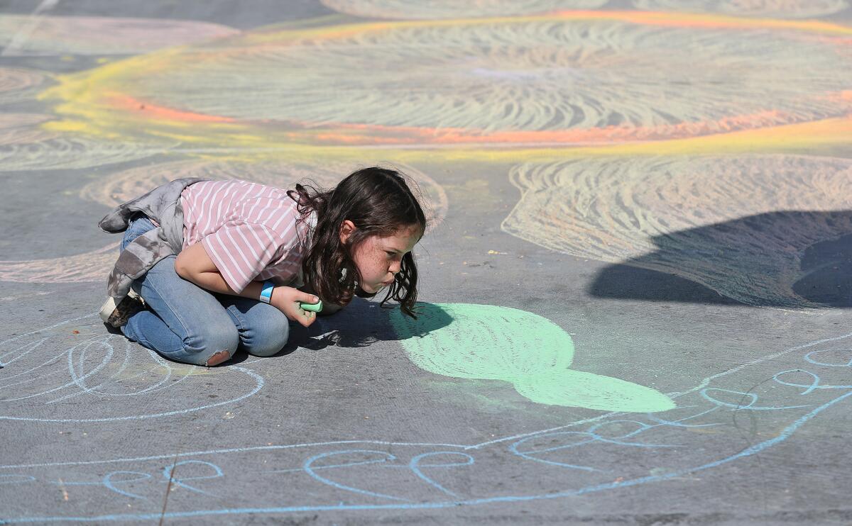 A youngster draws a giant flower pedal during the "Look Up" flash art experience on the playground.