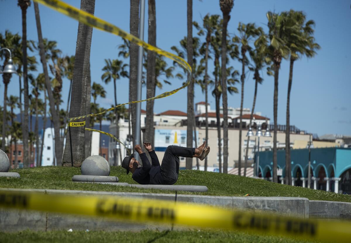 Raymond Bartlett exercises near caution tape at the basketball courts at Venice Beach.