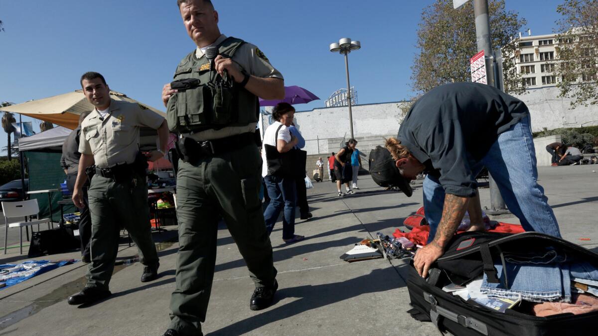 Kevin "Sippi" Moran, 49, right, packs up his wares after being told to do so by sheriff's deputies.