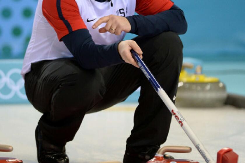 U.S. skip John Shuster checks the line of a shot during a match against Switzerland at the Sochi Olympics' Ice Cube Curling Center.