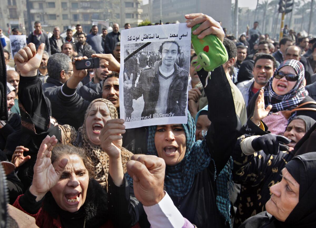 Relatives of Mohamed ElGindy, a 28-year-old Egyptian activist who died of injuries sustained during or after a protest last week, hold up his picture as they shout slogans against President Mohamed Morsi during a funeral procession in Cairo's Tahrir Square.