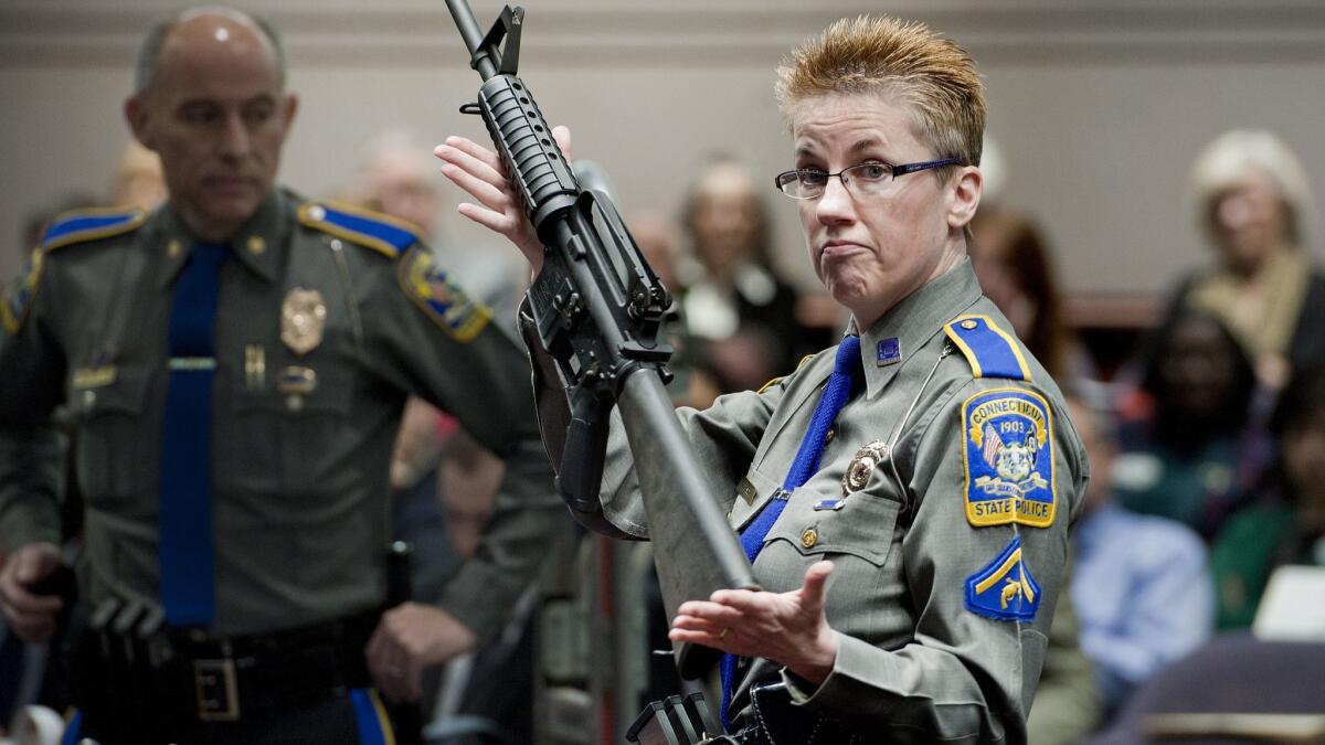 A firearms training unit detective holds a Bushmaster AR-15 rifle, the same make and model used by Adam Lanza in the 2012 Sandy Hook School shooting, during a hearing in Hartford, Conn. on Jan. 28, 2013.