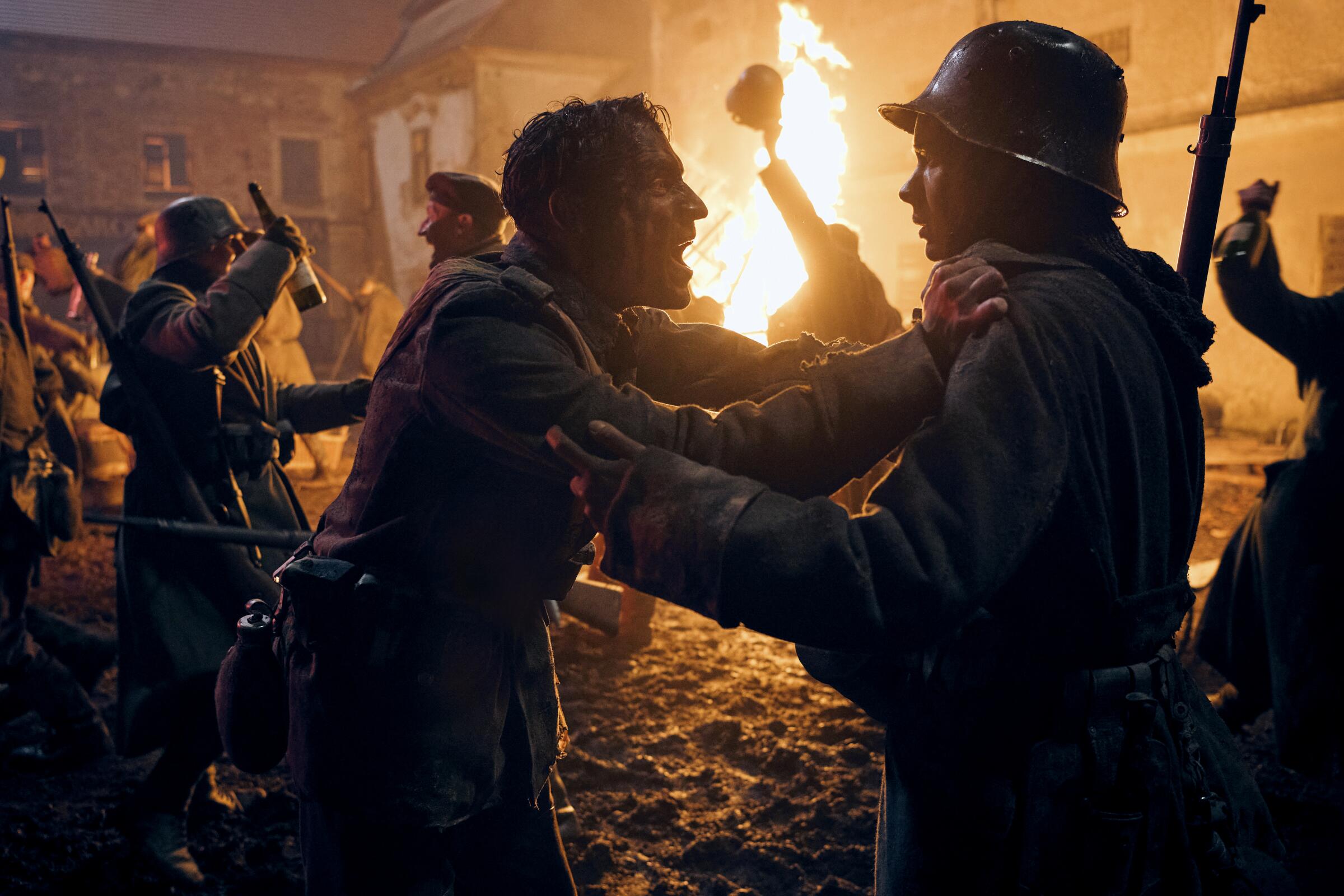 Two soldiers shout amid fires and celebrating in "All Quiet on the Western Front."