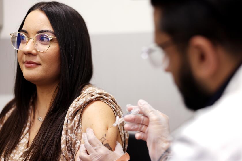 HUNTINGTON PARK-CA-AUGUST 28, 2024: Heidi Salguero, 32, of Bell, left, receives a flu vaccine from pharmacist Deep Patel, right, at CVS in Huntington Park on August 28, 2024. (Christina House / Los Angeles Times)