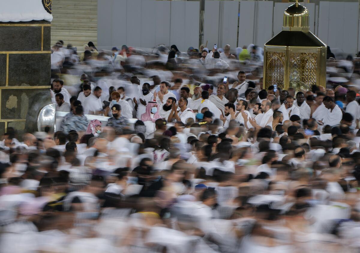 In this photo taken with low shutter speed, Muslim pilgrims pray as others circumambulate around the Kaaba, the cubic building at the Grand Mosque, in Mecca, Saudi Arabia, Wednesday, July 6, 2022. Muslim pilgrims are converging on Saudi Arabia's holy city of Mecca for the largest hajj since the coronavirus pandemic severely curtailed access to one of Islam's five pillars. (AP Photo/Amr Nabil)