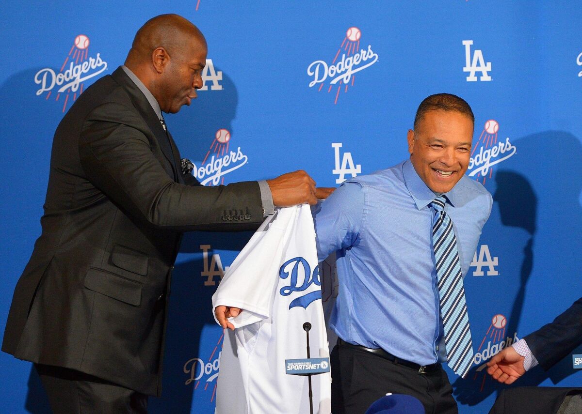 Los Angeles Dodgers owner Magic Johnson introduces new manager Dave Roberts and helps him with his new jersey during a press conference today at Dodger Stadium. Jayne Kamin-Oncea