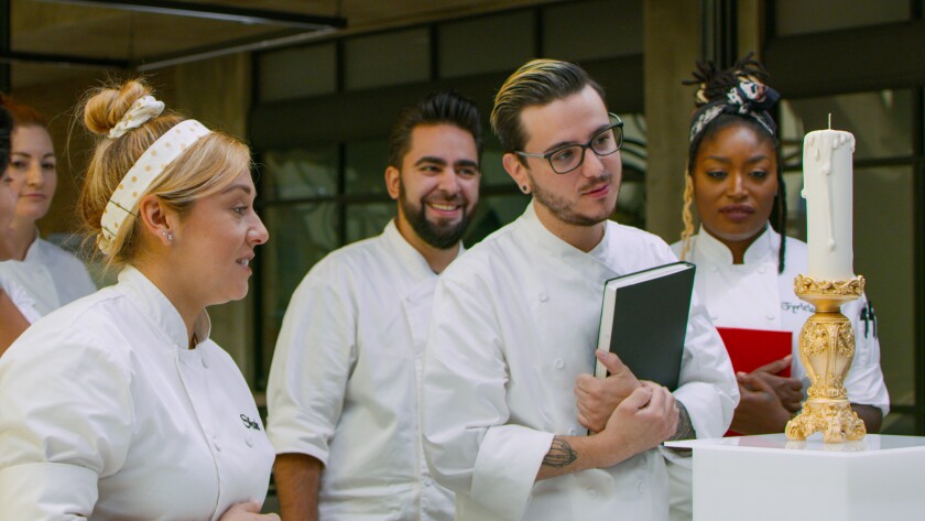 A group of chefs observe a lifelike candle and holder made from chocolate.