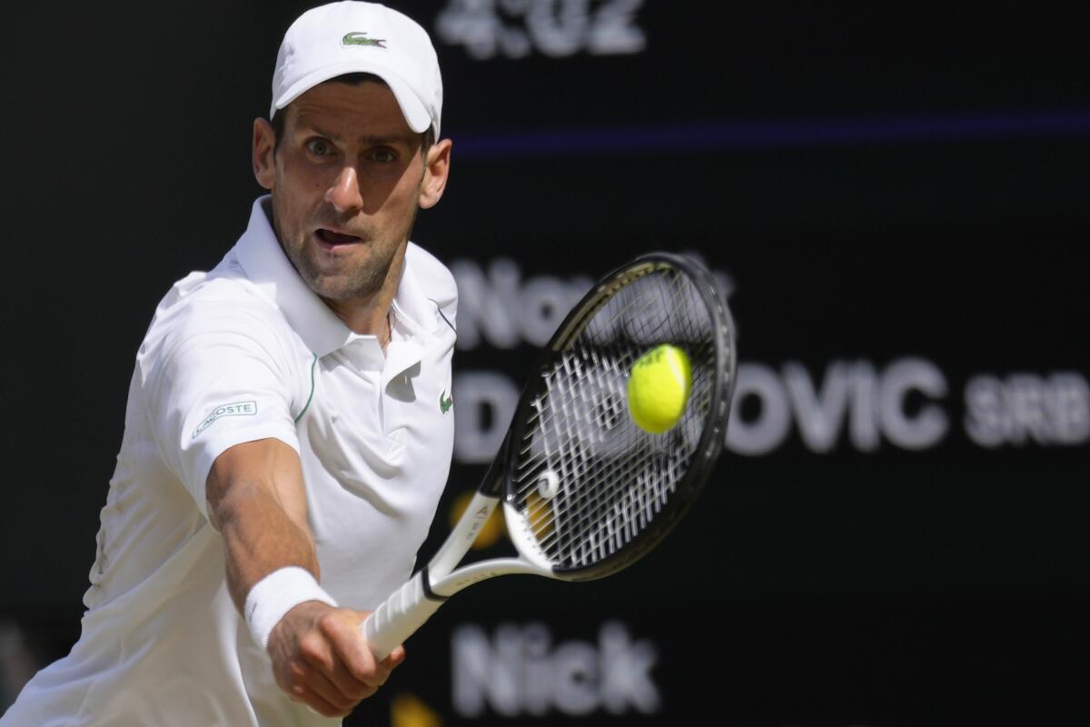 Novak Djokovic reaches to hit a backhand return against Nick Kyrgios in the Wimbledon men's final.