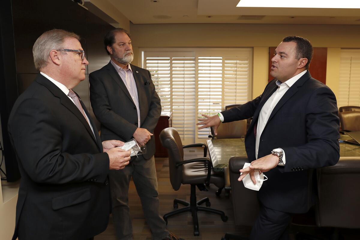 Trevor Theriot, president and chief executive of ManaMed Inc., right, speaks Friday with Robert Braithwaite, president and CEO of Hoag Hospital in Newport Beach, left, and state Sen. John Moorlach (R-Costa Mesa) as Theriot donated 5,000 N95 filtering respirator masks to Hoag.