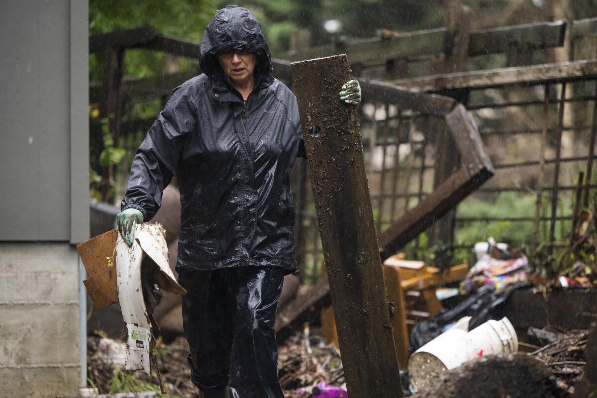 A resident clears debris from a yard after the San Lorenzo River overflowed 