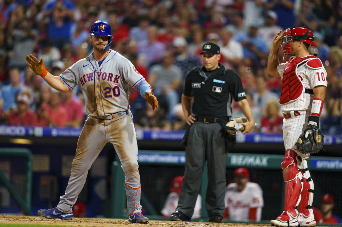 New York Mets' Pete Alonso, left, reacts to his home run as Philadelphia Phillies catcher J.T. Realmuto, right, looks on during the third inning of a baseball game, Friday, Aug. 19, 2022, in Philadelphia. (AP Photo/Chris Szagola)