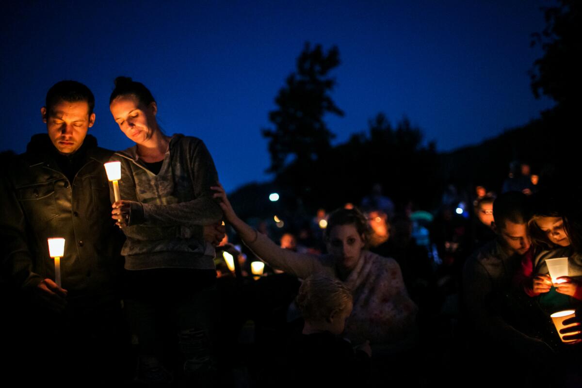 Residents mourn shooting victims at a vigil in Riverbend Park in Winston, Ore.