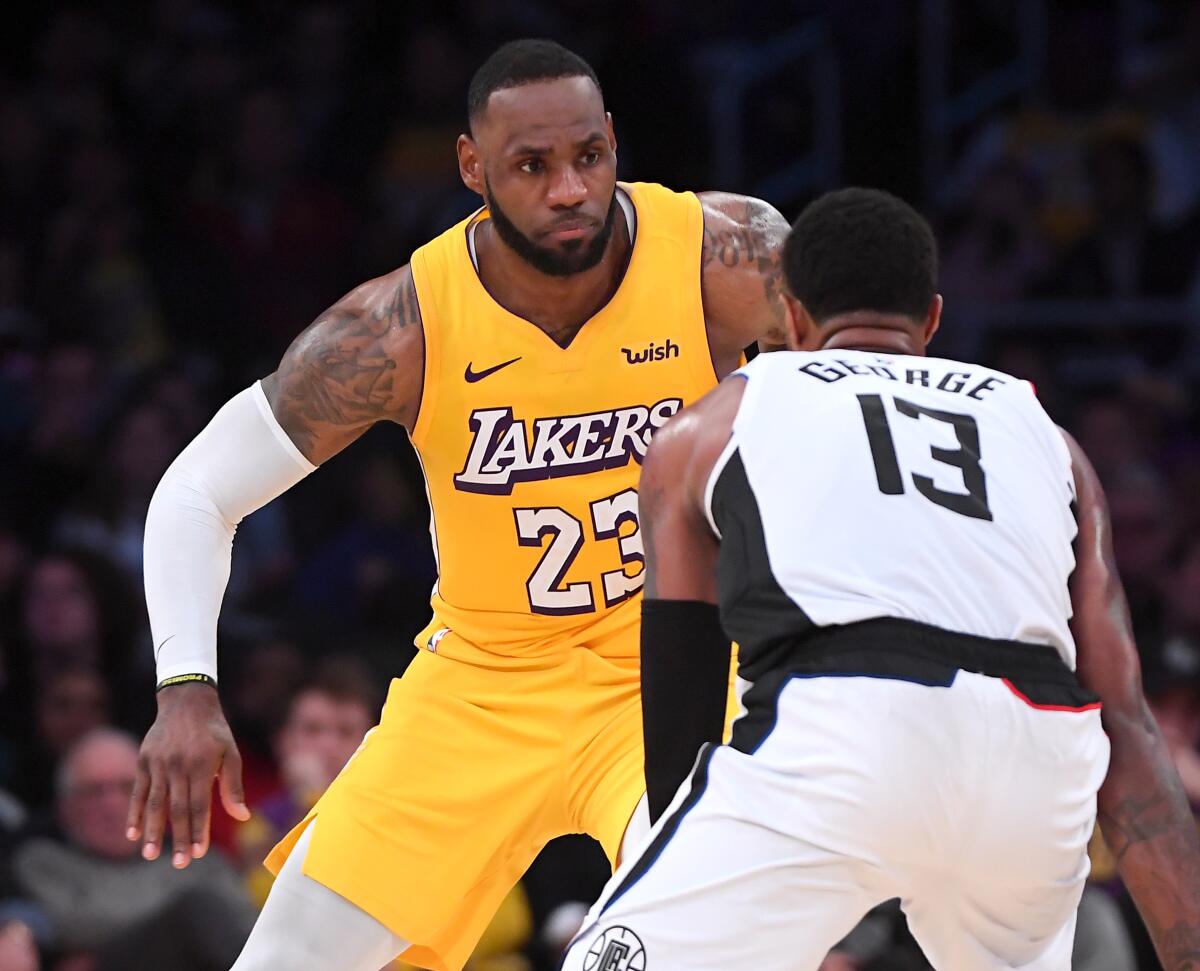 Lakers' LeBron James (23) guards Clippers' Paul George on Christmas Day at Staples Center. James will miss Saturday's game in Oklahoma City because of an illness.
