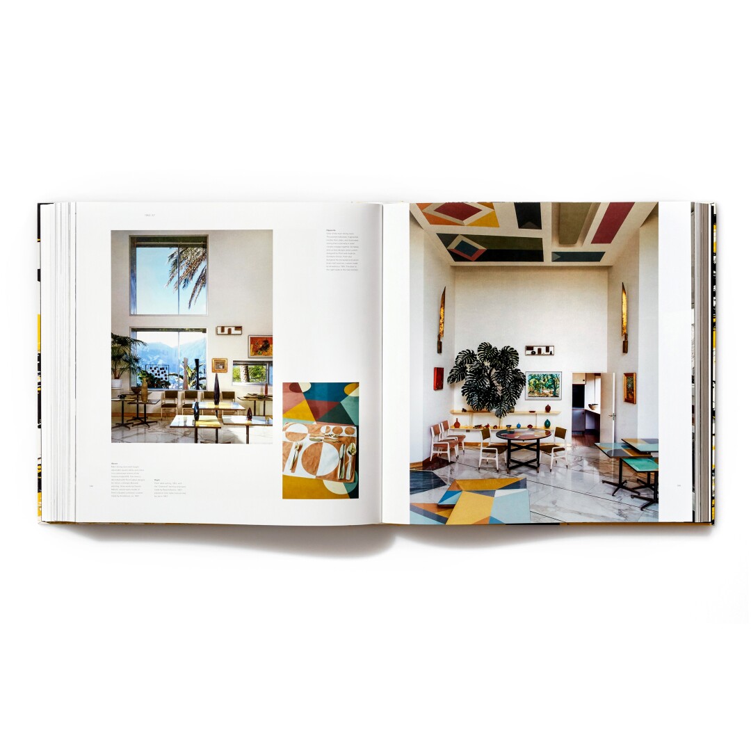 An architectural book is opened to a spread that reveals domestic interiors.