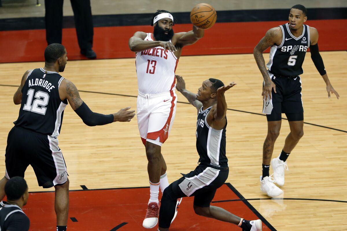 Houston Rockets guard James Harden (13) passes the ball over San Antonio Spurs forward LaMarcus Aldridge (12), guards Lonnie Walker IV, middle right, and Dejounte Murray (5) during the first half of an NBA basketball game Tuesday, Dec. 15, 2020, in Houston. (AP Photo/Michael Wyke)