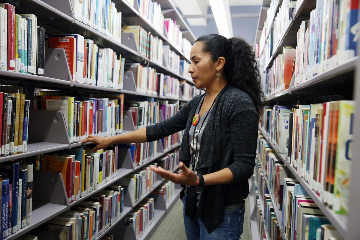 Librarian Ana Campos stands between library shelves. 